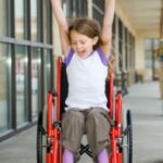 child in a wheelchair cheering
